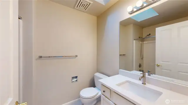 Updated hall bathroom, complete with a sleek quartz countertop vanity, and modern fixtures.