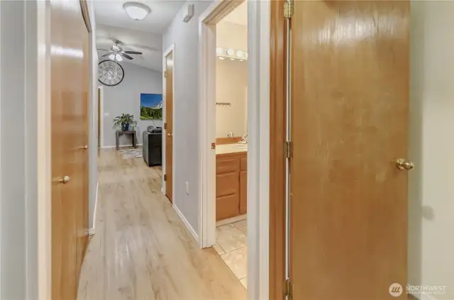 Hallway showing bathroom and bedroom doors, hallway closet contains the laundry