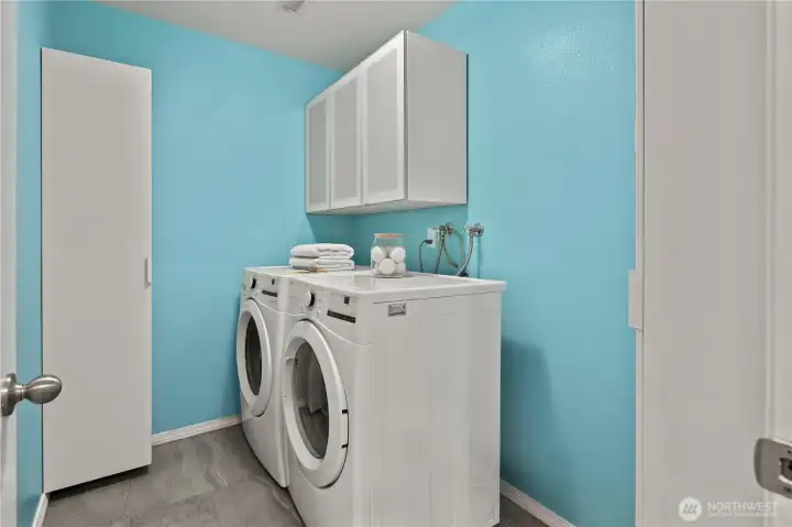 Dedicated laundry room featuring upper cabinets and practical storage