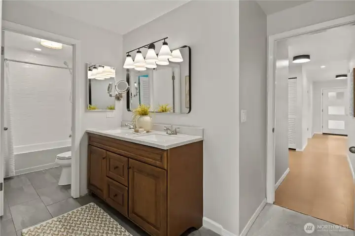Double-sink vanity with a wide mirror and bright, modern lighting