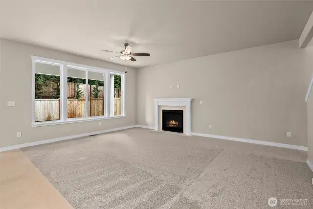 Cozy gas fireplace with mantle and tile surround. Living room ceiling fan is included.  Home under construction, photo for illustration only.