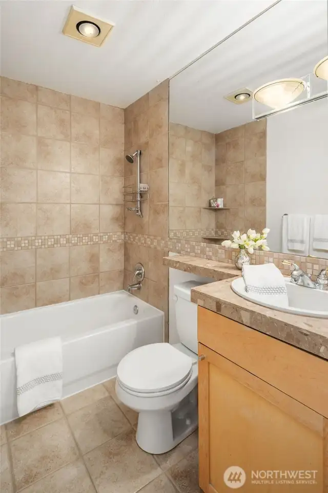 Featuring a marble vanity and elegant tiled accents, the shared bathroom also includes updated shower knobs and a brand-new medicine cabinet.