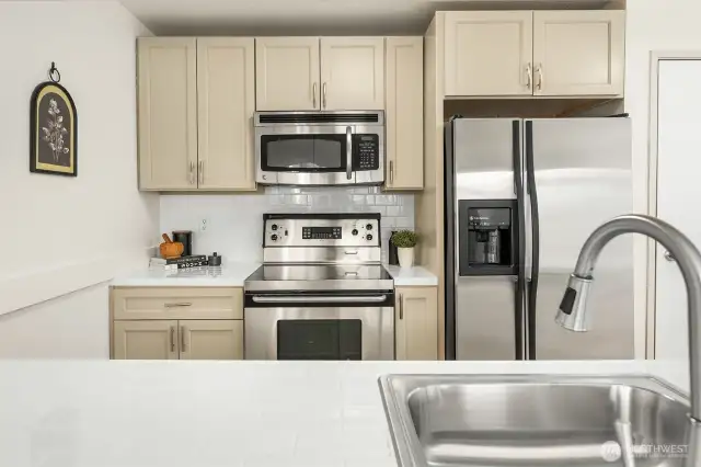 A stylish kitchen featuring brand-new stainless steel appliances, luxury LVP flooring, and an updated light fixture.