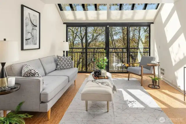 Natural light fills the living room through floor-to-ceiling windows and doors, enhanced by elegant atrium outdoor shades.