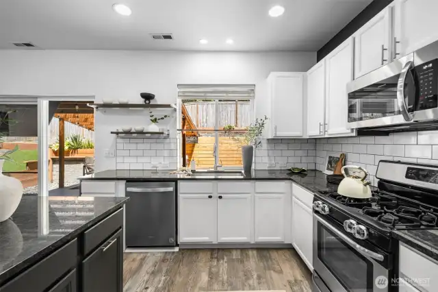 Refreshed kitchen featuring newer appliances, updated flooring, stylish tile backsplash, modern counters, fresh paint, and contemporary fixtures.