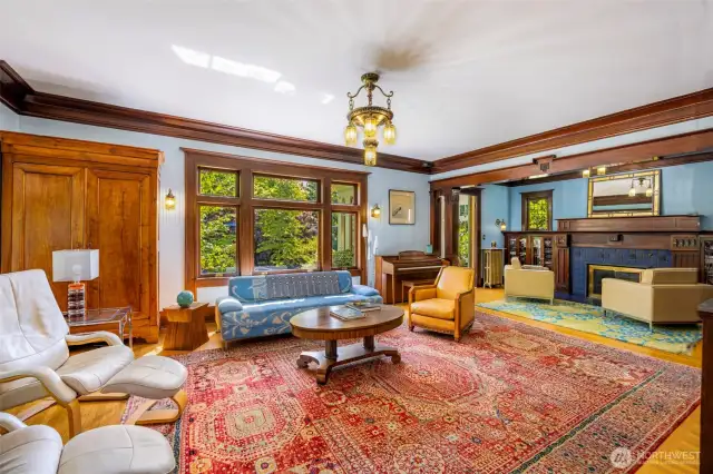 Bright living space with a stunning chandelier, abundant windows, and rich woodwork.