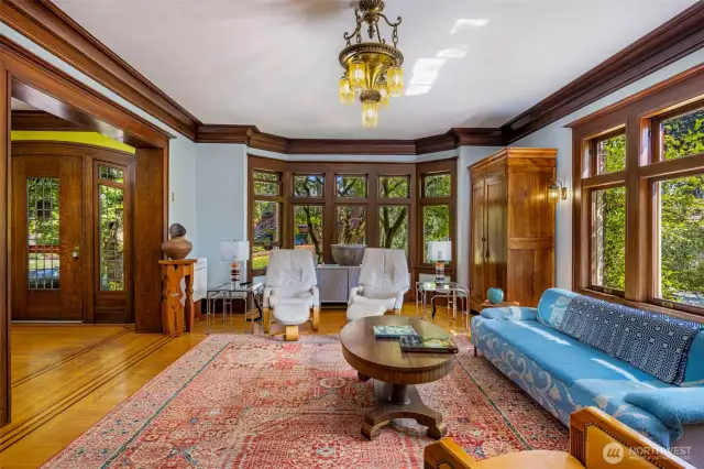 Beautiful original woodwork frames this spacious living room, with a glimpse of the classic front door in the background.