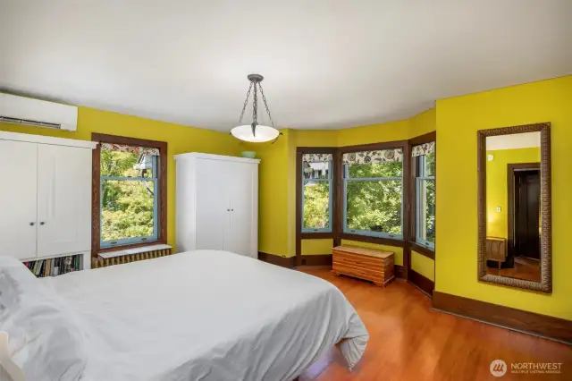 Bright primary suite with windows on two sides and warm wood floors.