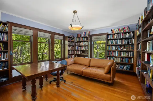 A stunning office or library wrapped in bookshelves.