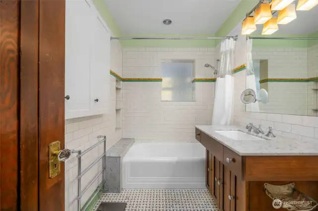 A second-floor bathroom with tile flooring, a wood cabinet, and white marbled countertops.