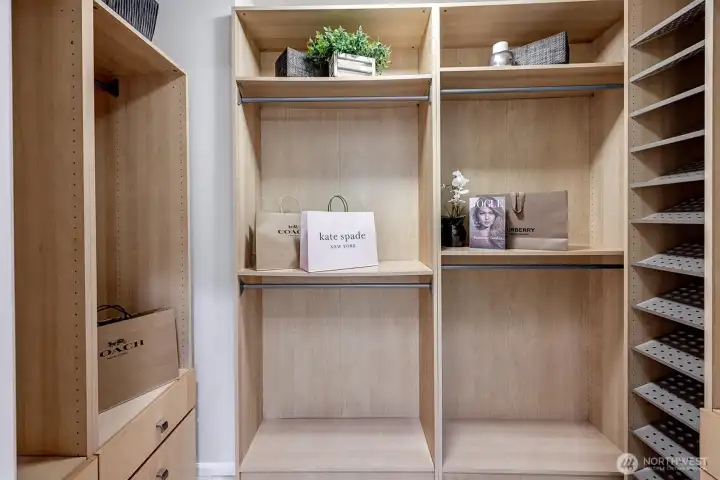 Primary closet with custom system. Hanging, drawers, shoe shelves and storage cubbies.