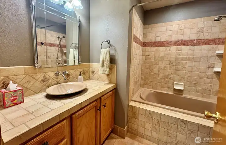 Full bath with tub/shower combo and tile surround.