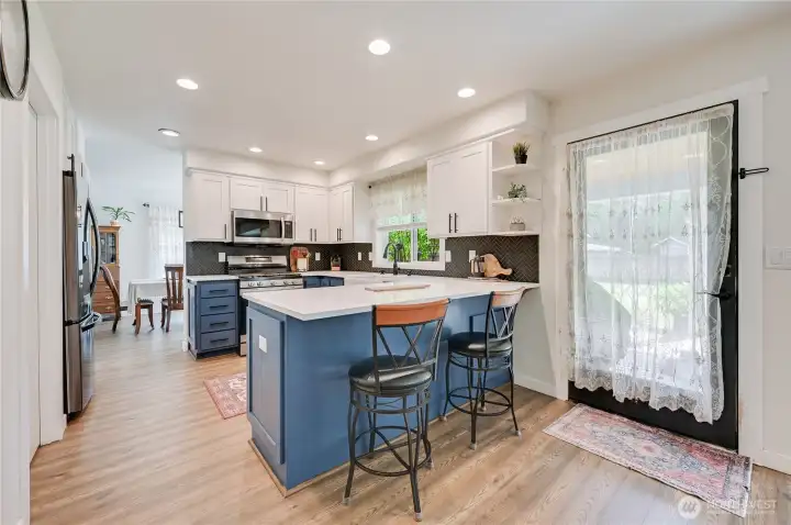 Quartz counters and tuxedo style blue and white cabinets.  Door leads to covered back deck.