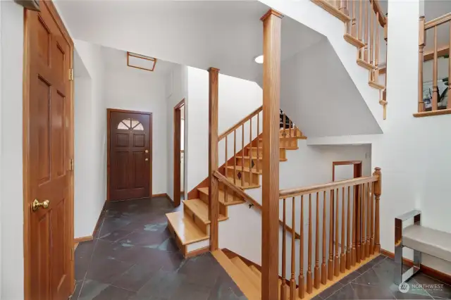 Timeless staircases with wood balustrades  keeps the elegant foyer feeling open and  welcoming! Durable slate flooring here keep  this area easy to care for!