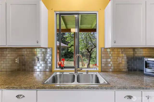 Slight retro feel with the backsplash here and the kitchen cabinetry knobs.  Nice view from the double sink into the backyard.