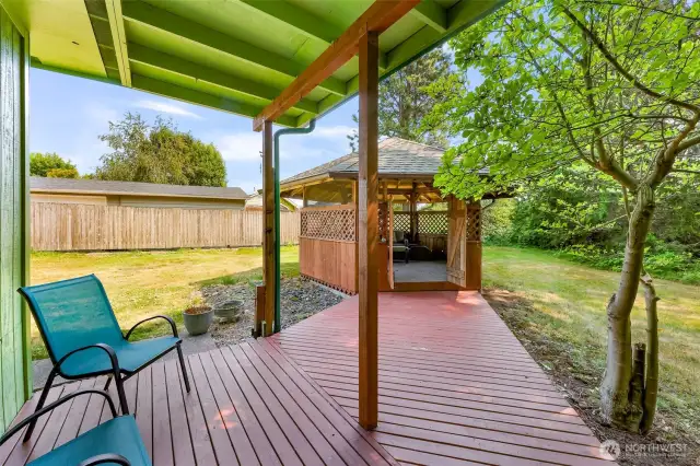 Back patio - decking leads to the quaint gazebo.  A firepit area behind the gazebo.  A treed patio gives a lot of privacy.  Fence in good condition with new posts is in the backyard.