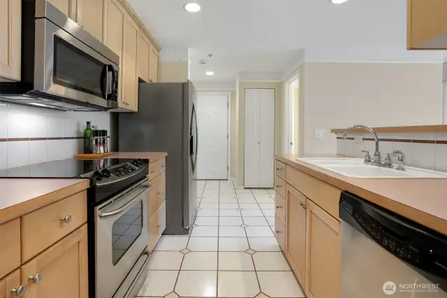 Looking back at the front entrance door (door to left). Behind the fridge is access to the second bedroom. The door on the right (see just a handle) is to the bathroom.
