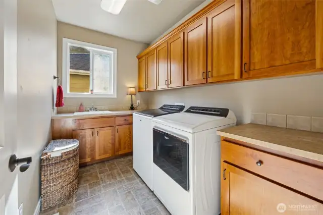 Main floor laundry room offers ultimate functionality with abundant cabinetry for storage, a deep utility sink for convenience, and a generous countertop perfect for folding and sorting clothes—making everyday chores a breeze!