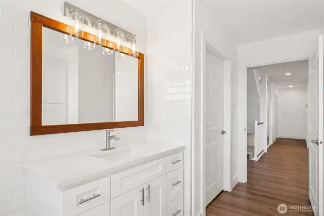Those beautiful finishes including subway tile to the ceiling and quartz countertops follow through the guest bath on the main living level.