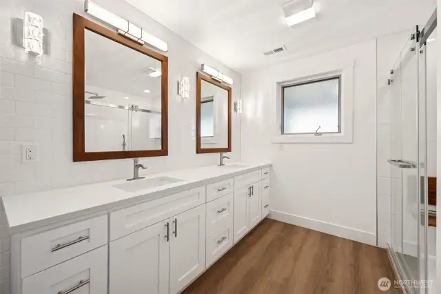 A primary bathroom with large double vanity, custom tile shower and lots of light.