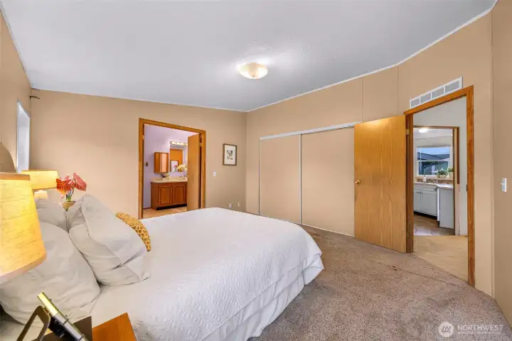 View from a corner of the primary bedroom, looking at the full bathroom (left center) to the kitchen (right).