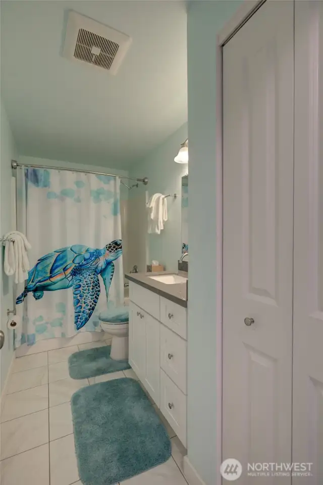 Beautiful bath with quartz countertops and tile floors, and a full linen closet.