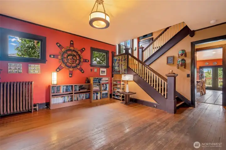 Stunning grand staircase in the entryway with original hardwood floors, classic radiator, and rich period character throughout.
