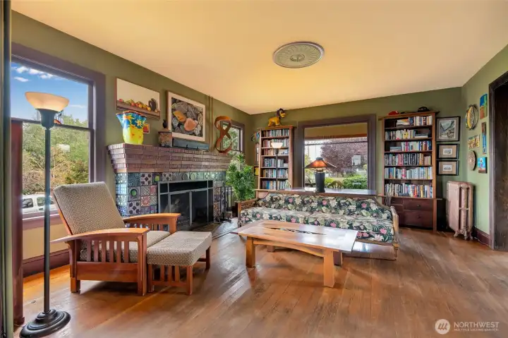 Another angle of the living room highlights the fireplace, Craftsman-style details, picture windows, and abundant natural light.