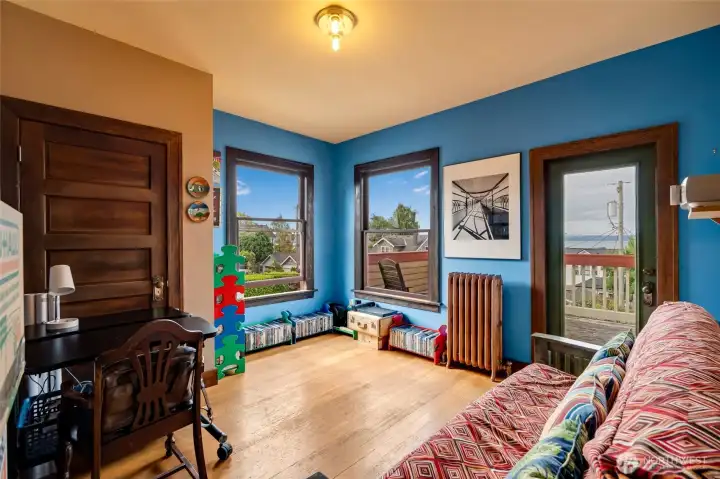 The fourth upstairs bedroom features hardwood floors, water views, an original radiator, and deck access.