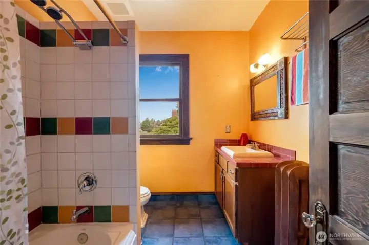 Upstairs full bath with colorful tile work, tub/shower, vanity, and classic period-appropriate character.