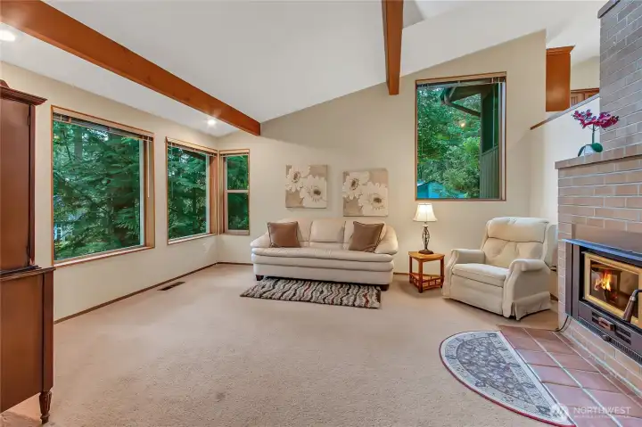 Living room with vaulted ceilings and exposed beams with large picture windows.