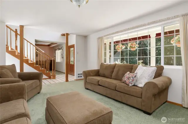 Light and bright living room with large windows with views of the the lush lawn and trees