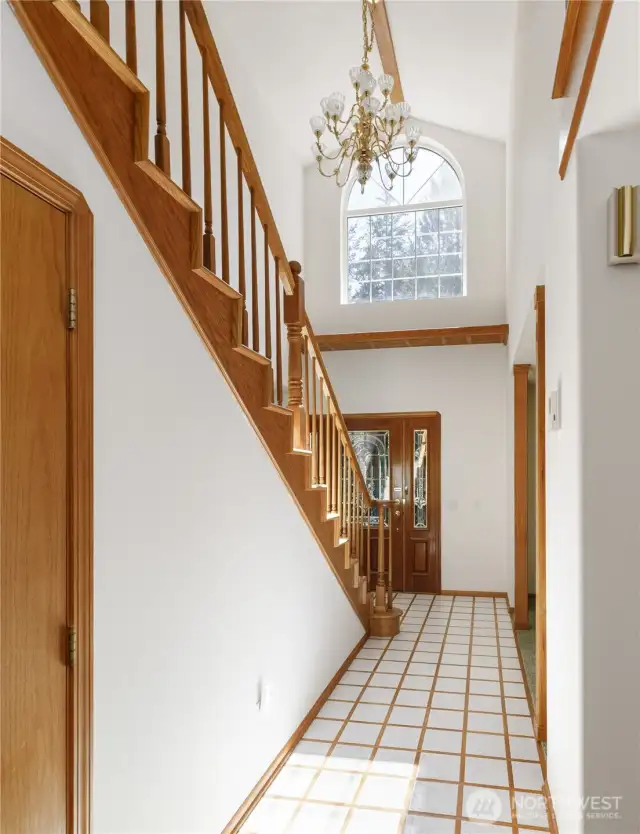 Light-filled entry with centerpiece crystal chandelier and an huge decorative wood shelf underneath window for seasonal decorating, plants, etc. Also, additional storage space under the stairs.
