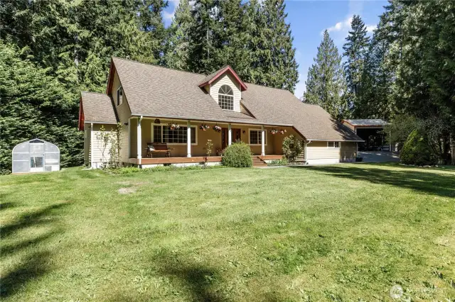 Expansive front lawn and greenhouse on left