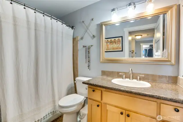 The main floor full bathroom impresses with sleek granite counters, durable tile flooring, and a stylish tile tub surround, blending functionality with modern flair.