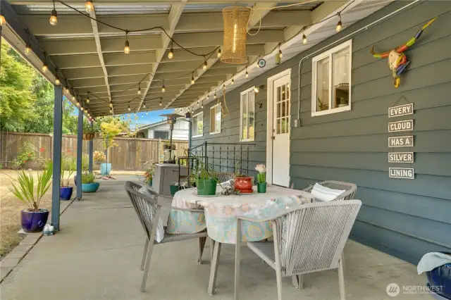 The covered patio, adorned with festive party lights, creates a vibrant vibe for year-round entertaining, perfect for BBQs or late-night hangouts with friends.
