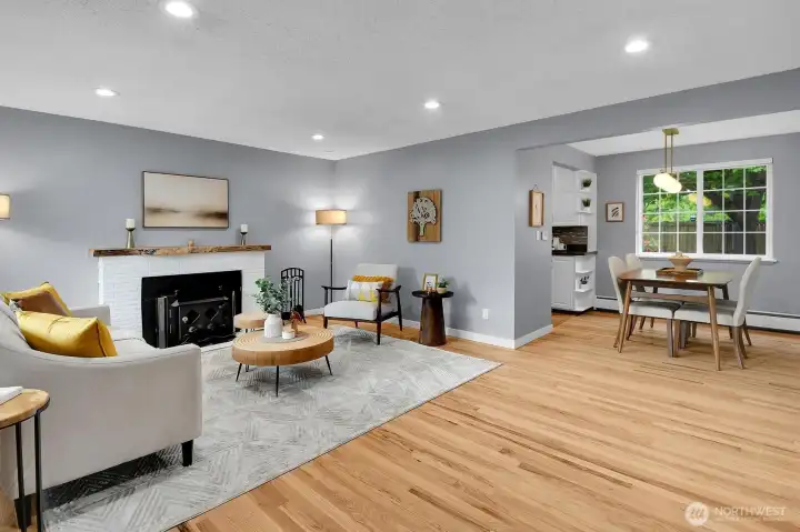 Open-concept living and dining space with large picture windows and warm hardwood flooring in desirable West Seattle neighborhood.