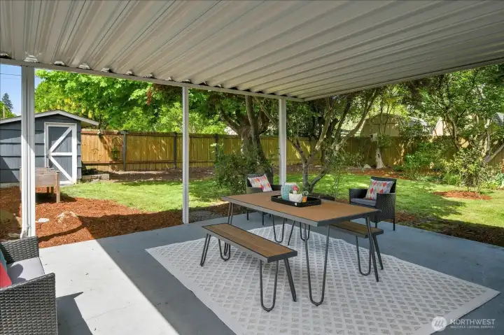 Covered backyard patio perfect for entertaining, outdoor dining, and year-round enjoyment beneath mature trees.