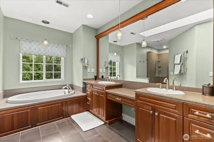 Spa-inspired primary bath featuring soaking tub, dual vanities, and dual-head shower