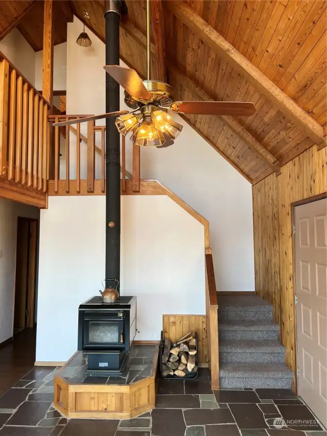 Slate floors surround the entrance, wood stove and leading to the upstairs loft and primary bedroom.
