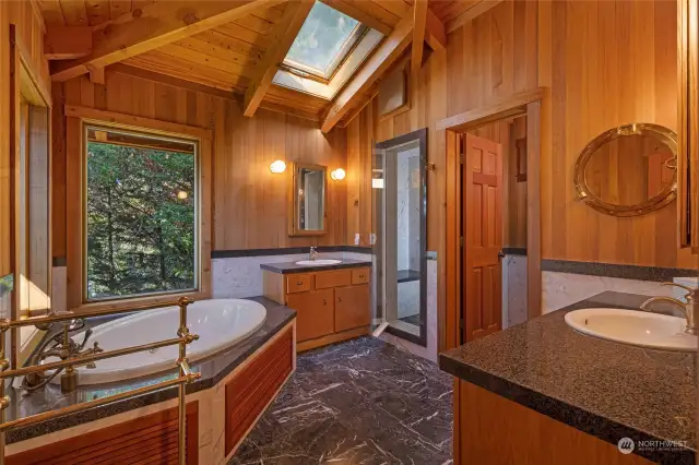 The primary ensuite bathroom with jetted tub, steam shower, dual vanities, marble floors and a separate toilet room.