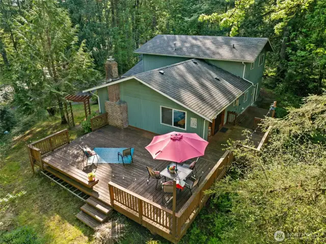 An aerial view of the South East side of the home shows the expansive decking and privacy trees.