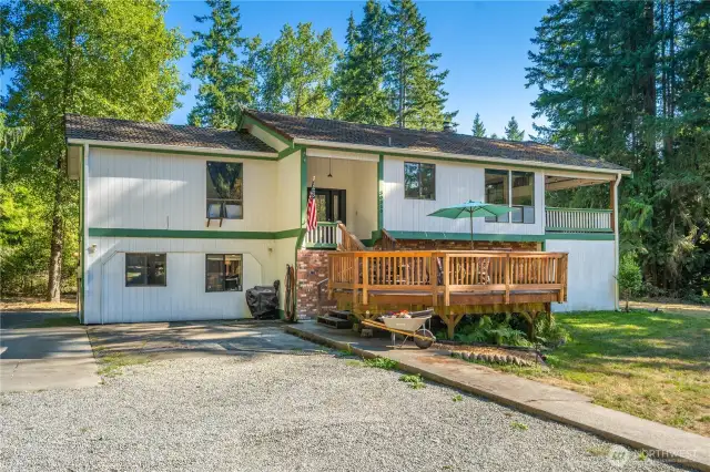 Front approach highlighting generous driveway space, gravel parking area, and welcoming covered entry