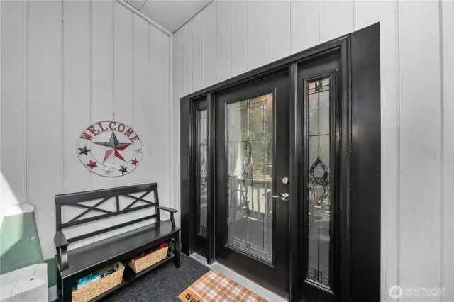 Welcoming covered porch with decorative glass double doors, providing sheltered access and a charming first impression.