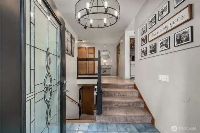 Tiled entryway opening to split-level stairs, with sightlines to upper living areas and lower-level spaces.