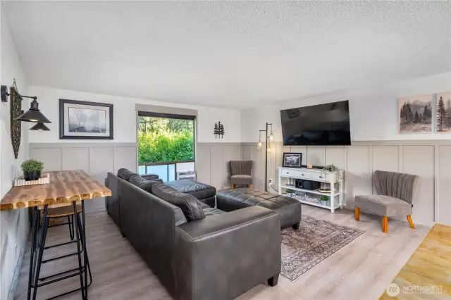 Spacious main-level living room with large picture window bringing in natural light and views of the surrounding greenery.