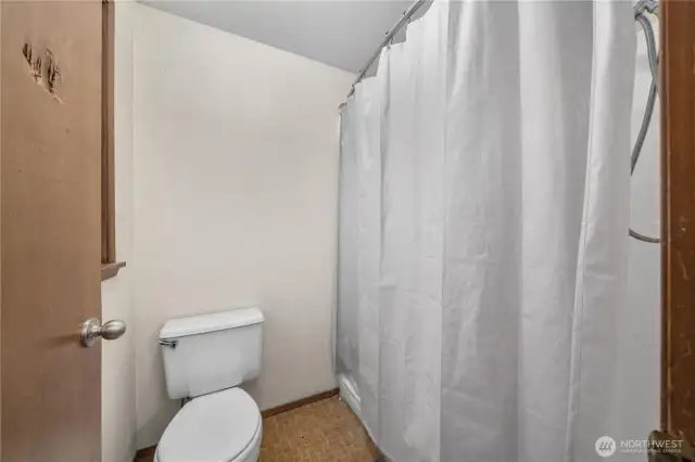 Second view of the private en suite showcasing the shower area with curtain enclosure, offering practicality and easy upkeep.