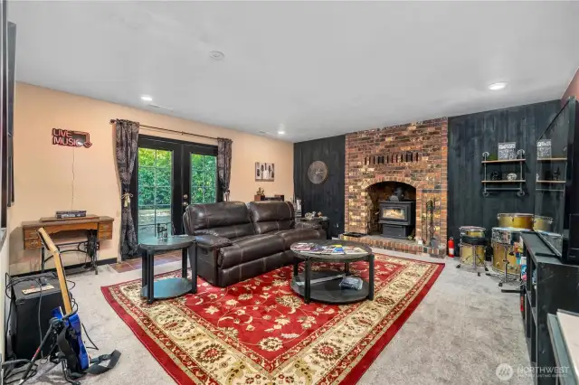 A cozy and inviting family space with a striking brick fireplace and wood stove, ideal for warmth and ambiance. French doors open to the outdoors, bringing in natural light and offering easy access for indoor-outdoor living. The open layout easily accommodates seating, music, and entertainment areas.