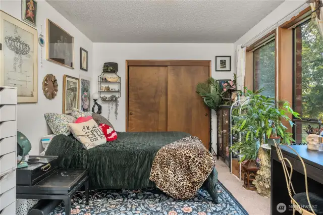 From this angle, the lower level bedroom showcases its cozy sleeping space. The expansive window not only brightens the room but also offers views of the surrounding trees, creating a peaceful retreat.