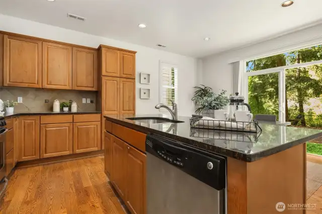 Oversized island in kitchen looking out to backyard through sliding glass doors.
